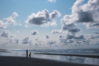 Mother and child at beach against sky