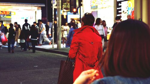 Rear view of people sitting on street in city