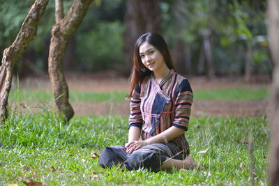 Portrait of young woman sitting on field
