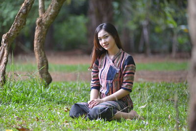 Portrait of smiling young woman sitting on land