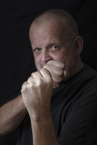 Portrait of man showing fist against black background