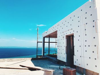 Built structure by sea against blue sky