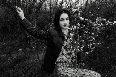 Portrait of young woman standing on field in forest