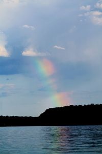 Scenic view of rainbow over sea against sky