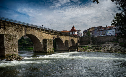 Bridge over river against cloudy sky