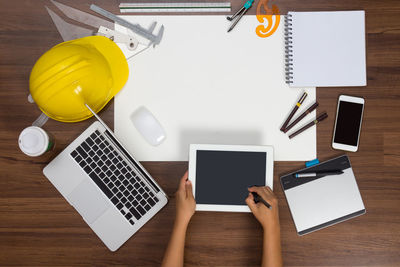 Cropped hands of architect using digital tablet at desk