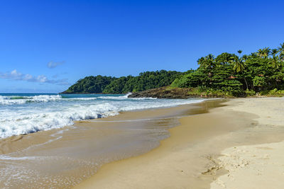 Scenic view of beach against clear blue sky