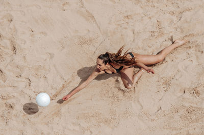 High angle view of woman playing volleyball on sand at beach