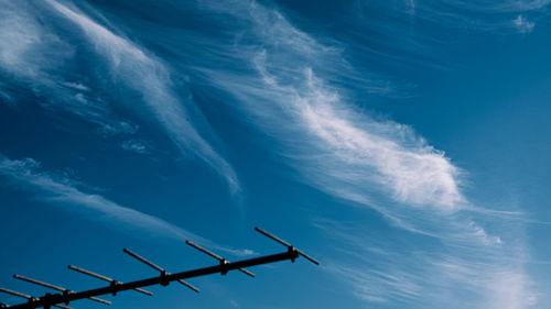 Low angle view of silhouette airplane against blue sky