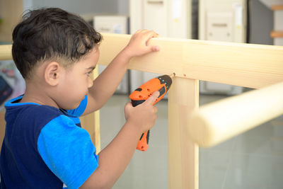 Boy drilling wood at home