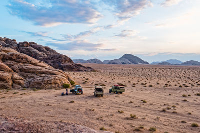 Off-road vehicles at desert against sky