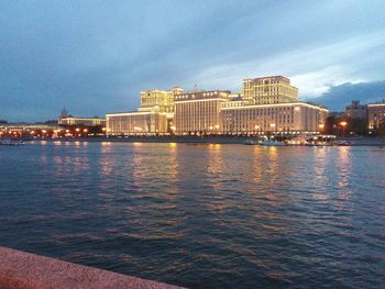 City at waterfront against cloudy sky