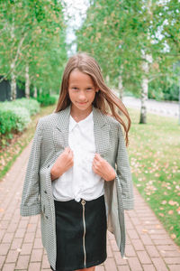 Portrait of smiling young woman standing on footpath