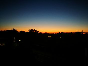 Silhouette city against clear sky during sunset
