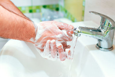 Close-up of man hand with faucet in water
