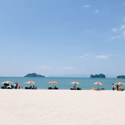 People on beach against blue sky