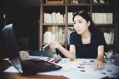 Woman using mobile phone while sitting on table