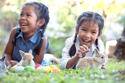Smiling siblings with rabbits lying on grass