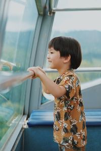 Side view of young woman looking through window