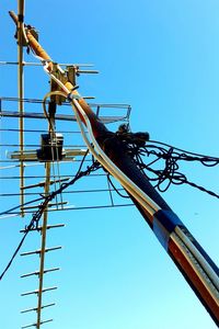 Low angle view of electricity pylon against blue sky