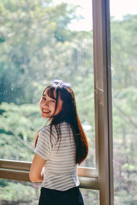 Young woman standing against window