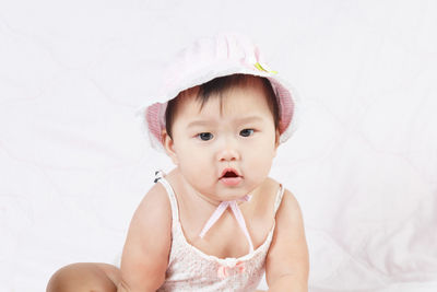 Cute baby girl sitting on bed at home