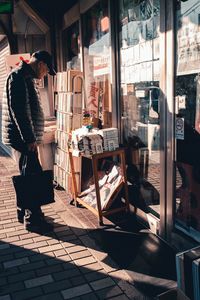 Man standing on footpath seen through glass window