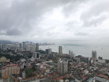 High angle view of city and sea against cloudy sky