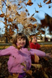 Happy girl playing in park during autumn