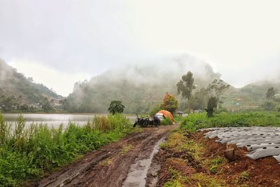 People on road by mountain against sky