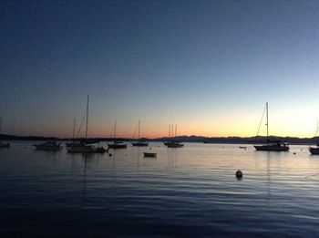 Sailboats in sea at sunset