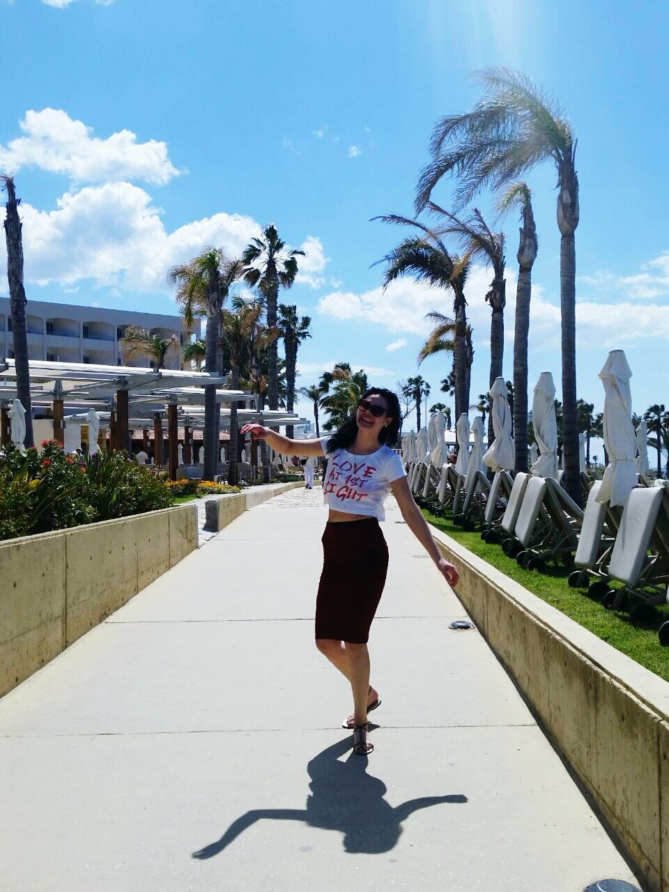 full length, building exterior, architecture, built structure, sky, rear view, lifestyles, casual clothing, the way forward, tree, leisure activity, palm tree, walking, city, sunlight, cloud, day, person