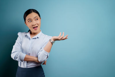 Portrait of smiling young woman against blue background