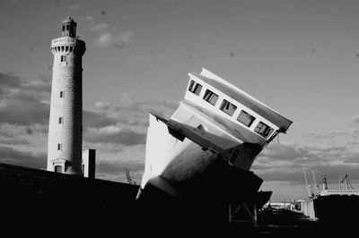 Low angle view of lighthouse by building against sky