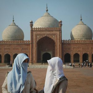 Friends wearing religious dress while standing against mosque