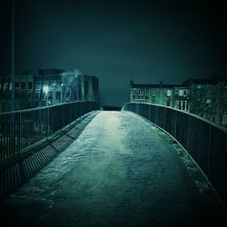 Illuminated footbridge against sky at night