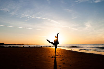 Silhouette of person on beach against sky during sunrise