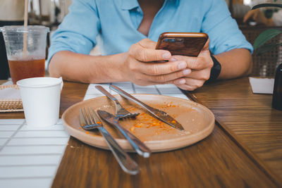 Midsection of man using mobile phone on table