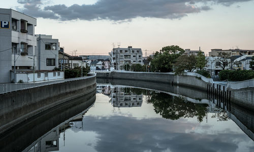 Bridge over river by buildings against sky in city