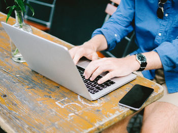 Midsection of man using mobile phone on table