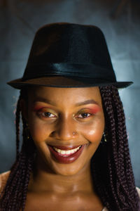Close-up portrait of smiling young woman wearing hat at home