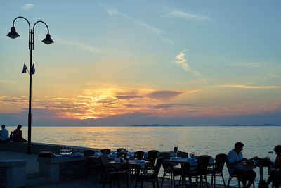 Silhouette people on beach against sky during sunset