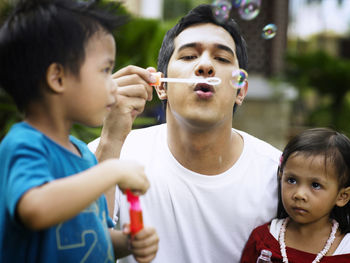 Close-up of family blowing bubble at park