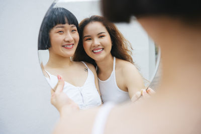 Reflection of lesbian sisters holding mirror outdoors