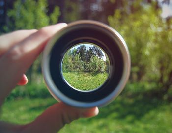 Cropped image of hand holding macro lens on field