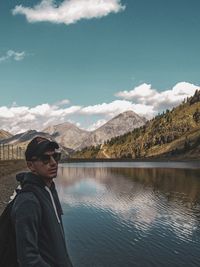 Side view of man wearing sunglasses standing by lake