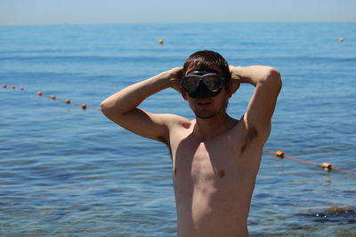 Shirtless man standing in sea against sky