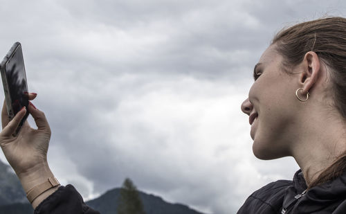 Portrait of man holding camera against sky