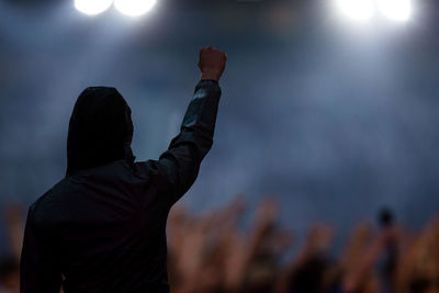 Rear view of man raising fist in crowd