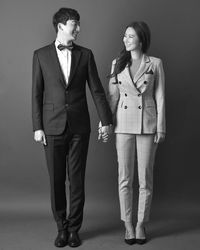 Portrait of young couple standing against gray background